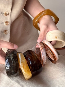 Close-up of resin cuff bracelets in amber and marble patterns with irregular shapes