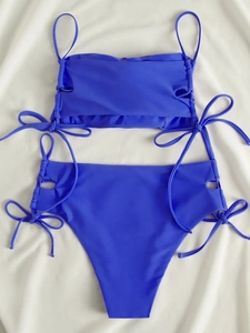 Close-up of royal blue bikini with side drawstring hollow details on white fabric