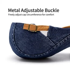 Detailed view of denim beret with adjustable brown strap and bronze metal buckle