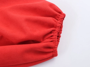 Détail du poignet élastique d'une robe rouge en suédine montrant la texture du tricotage