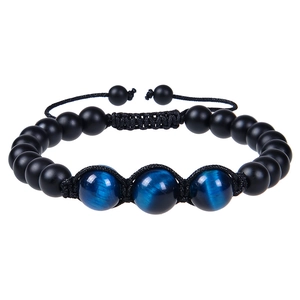Macro detail of hand-woven 12mm tiger eye beads on an adjustable matte black bracelet