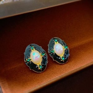 Gros plan de boucles d'oreilles vintage avec émail noir et pierres d'opale irisées