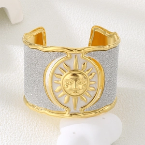 Detail of sun relief pattern on gold and silver stainless steel wide cuff bracelet
