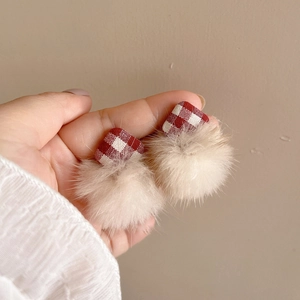 Close-up of red plaid fabric earring with a soft cream plush pompom dangle