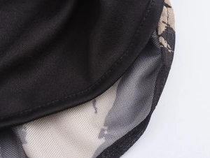 Detail van zwarte mesh en beige bloemenstof lagen met nauwkeurige stiksels