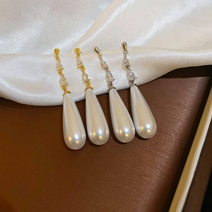 Detail of drop-shaped pearl earrings with gold plating and cubic zirconia accents