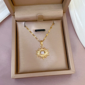 Collana occhio del male placcata in oro con zirconi in una scatola per gioielli beige su tessuto