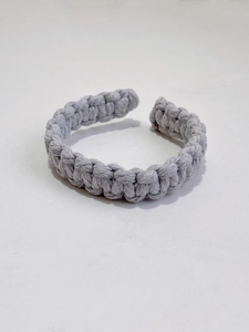 Detailed close-up of gray hand-woven cotton curtain tieback showing dense knot texture