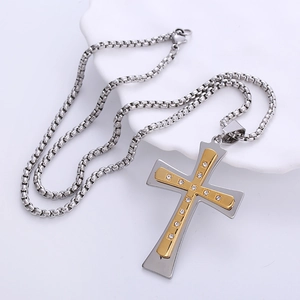 Two-tone stainless steel cross necklace with CNC set rhinestones on a white display pedestal