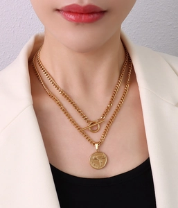 Close-up of double-layer gold curb chain with OT clasp and gun coin pendant