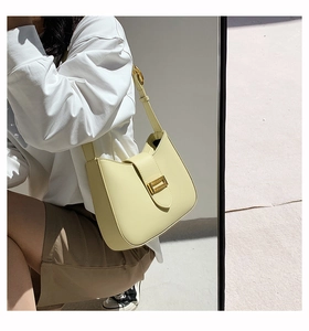 Detail of cream baguette shoulder bag featuring a gold buckle on soft matte leather strap
