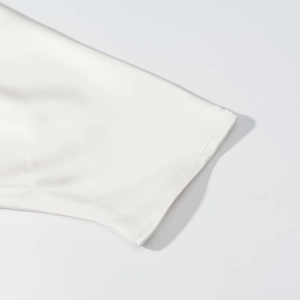 Gros plan des coutures précises et du tissu satiné soyeux sur la manche de la robe blanche