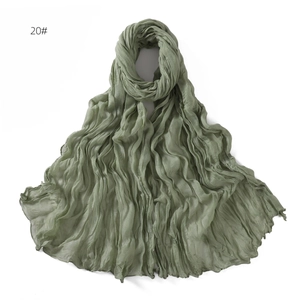 Detail shot of sage green crinkle texture scarf with natural frayed edges in soft gauze