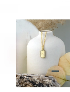 Detail view of a gold-plated square pendant necklace with letter K and zircon inlay