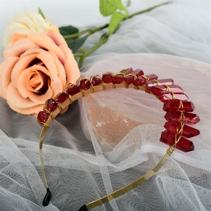Close-up of handmade golden crown headband with raw red crystals on floral lace background
