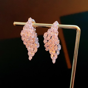 Close-up of golden earrings with pink and clear marquise-cut zircon stones on a display