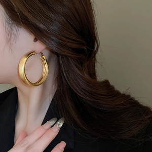 Close-up of thick gold-plated hoop earring with polished mirror finish on model