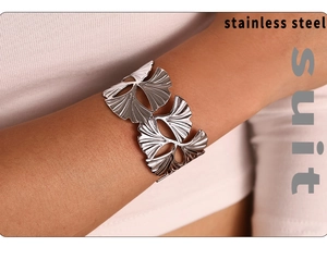 Detailed view of hollow ginkgo leaf design on a wide polished stainless steel bangle