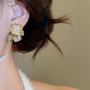 Detail of vintage gold flower earrings with white pearl center on model