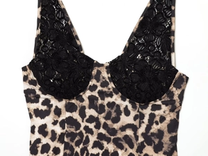 Detailed close-up of leopard print fabric with delicate black lace stitching on neckline