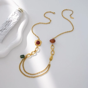 Dettaglio della collana vintage dorata con perle di resina e ciondolo a forma di foglia