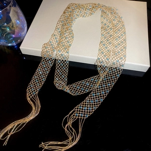 Detail of gold mesh necklace with light blue crystals and elegant long fringe tassels
