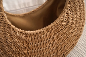 Close-up of woven straw texture and brown fabric lining of handmade shoulder bag