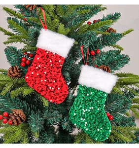 Detail of red and green sequined Christmas stockings with plush cuffs hanging on a tree