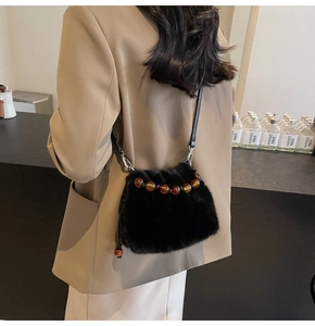 Detail of black faux fur bucket bag featuring amber beads and a slender shoulder strap