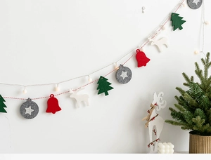 Guirlande de Noël en feutre minimaliste avec rennes et sapins sur mur blanc