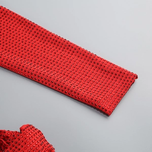 Close-up of red evening dress fabric with dense sparkling rhinestones and knit texture