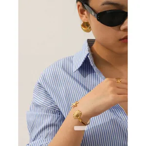 Detail shot of 18K gold starfish and seashell jewelry set worn with fashion accessories