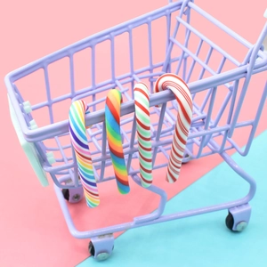 Miniature Christmas candy cane charms hanging on a purple toy cart for DIY crafts