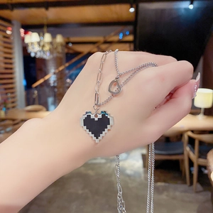 Vue détaillée du collier superposé avec cœur noir pixelisé et petit pendentif argenté