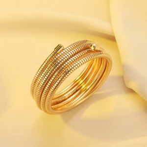 Detail of gold multi-layer spiral cuff with snake bone texture on silk background