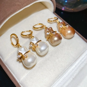 Vue macro de boucles d'oreilles en perles baroques plaquées or 18 carats avec nœud zircon