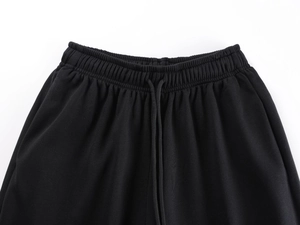 Detail of high-waist elastic waistband with matching drawstring on black sweatpants