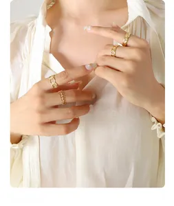 Detail of stacked gold geometric rings with chain link and hollow leaf designs on hand