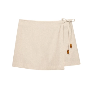 Mini-jupe portefeuille beige en lin avec lien latéral et détails de perles brunes