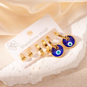 Gold stainless steel evil eye earring set featuring studs and hoops on a silk background