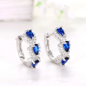 Detailed close-up of silver earrings with pear-cut blue zircon and pavé setting
