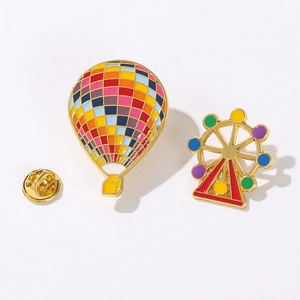Colorful hot air balloon and Ferris wheel enamel pins with golden metal base on white background