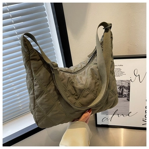 Detail of army green quilted nylon shoulder bag with adjustable strap and zipper closure