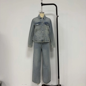 Detail view of light blue denim jacket and wide-leg trousers set on a display rack