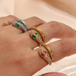 Close-up of gold and silver snake rings with red and green gemstone eyes on fingers