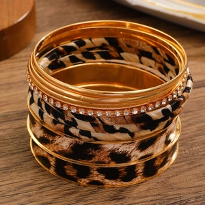 Macro shot of layered vintage leopard print bangles and gold crystal bracelets