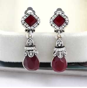 Detail of vintage bohemian silver clip-on earrings with red teardrop gemstones and crystals
