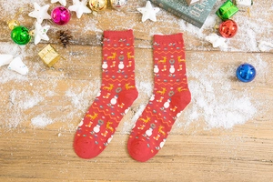 Detailed view of red Christmas socks with reindeer patterns on a rustic wooden floor