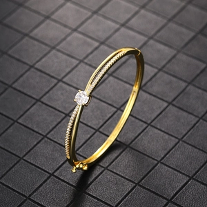 Detail of gold cross bracelet featuring pave-set cubic zirconia on textured background