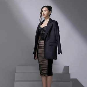 Detail eines Netz-Bodycon-Kleides mit Fischgräten-Korsett und schickem schwarzem Blazer